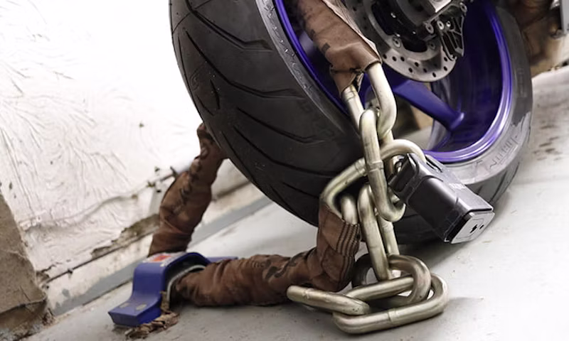 Heavy chain lock secured around a parked motorbike's wheel